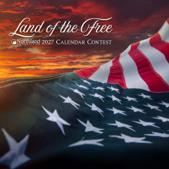 A photo of an American Flag waving in a sunrise.